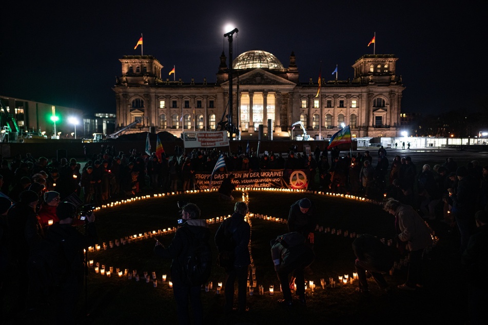 Mit einem Peace-Zeichen aus Kerzen demonstrieren am Freitag hunderte Menschen in Berlin für Frieden und Gedenken der Opfer in der Ukraine.
