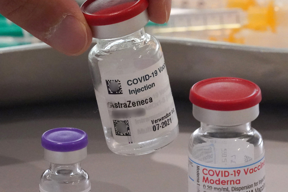 Ein Mitarbeiter des Impfzentrums in den Messehallen nimmt eine Impfdose vom Impfstoff Astrazeneca vom Tisch. Links im Bild steht eine Impfdose vom Impfstoff Biontech, rechts im Bild steht eine Impfdose vom Impfstoff Moderna.