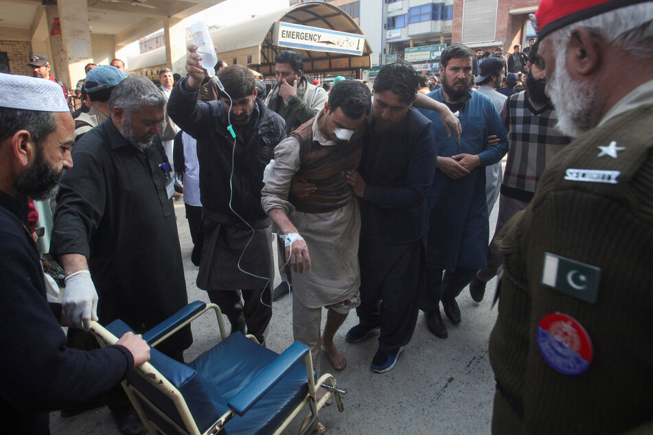 Men move an injured victim to hospital premises in Peshawar, Pakistan, after a likely suicide blast in a mosque on January 30, 2023.