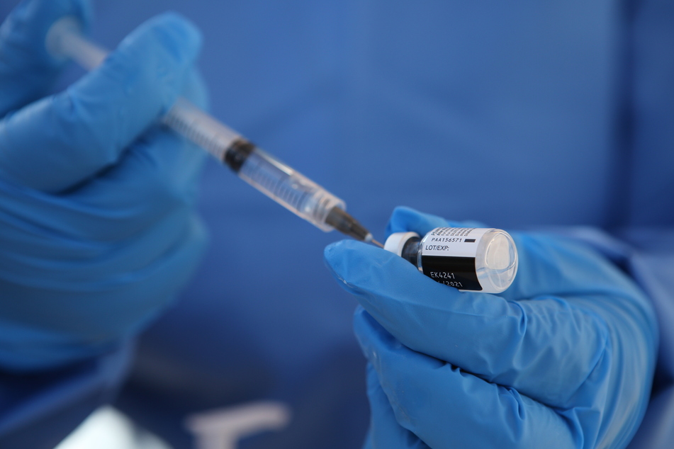 Ein medizinischer Mitarbeiter entnimmt mit einer Spritze eine Dosis des Corona-Impfstoffes der Unternehmen Biontech und Pfizer