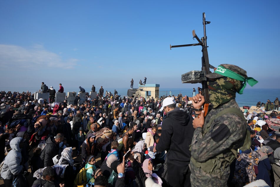 Ein Hamas-Kämpfer hebt seine Waffe, während vertriebene Palästinenser in ihre Häuser im nördlichen Gazastreifen zurückkehren.