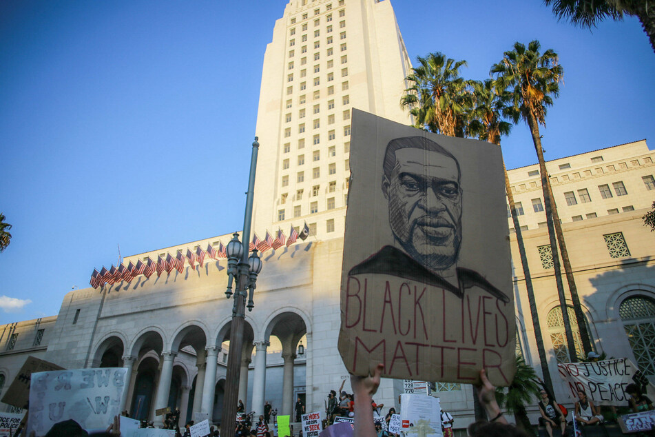 A protester holds a sign depicting George Floyd in front of Los Angeles City Hall.