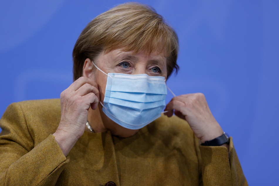 Bundeskanzlerin Angela Merkel (CDU) nimmt ihre Gesichtsmaske vor ihrer Pressekonferenz ab.