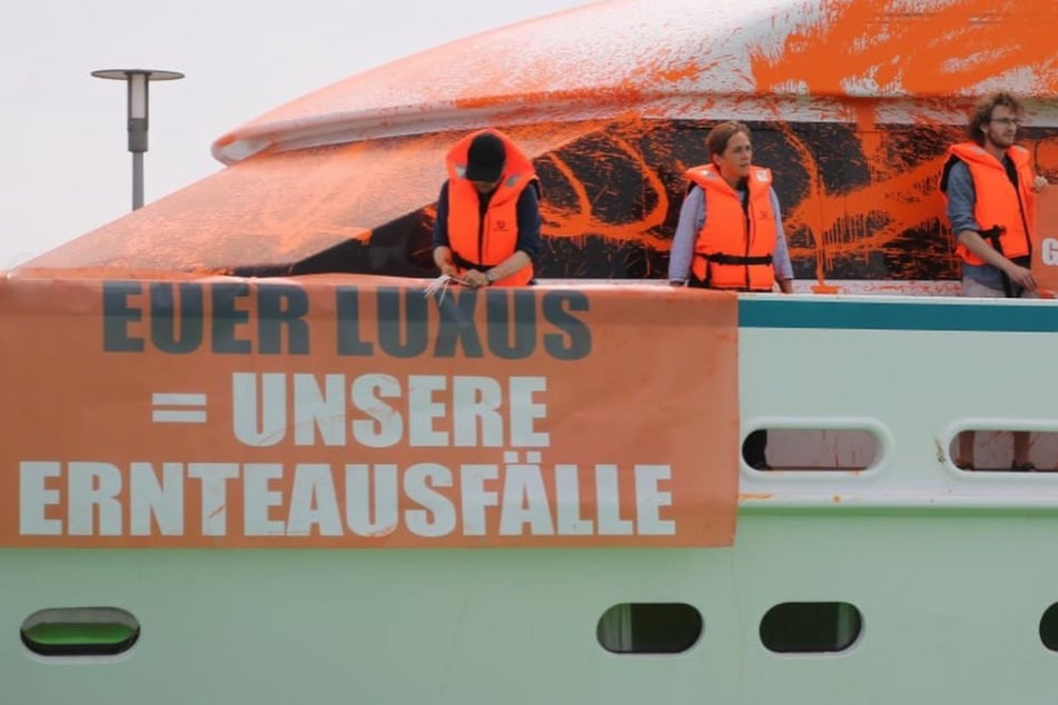 Aktivist*innen protestieren an Board einer Yacht.