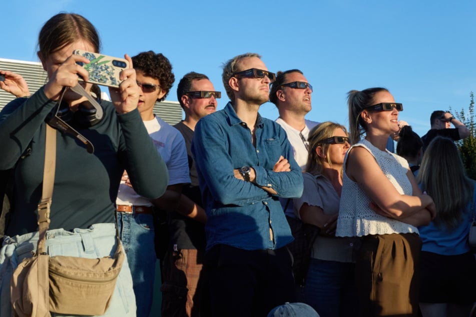 Besucher betrachten auf dem Dach des Grünen Bunkers die partielle Sonnenfinsternis.