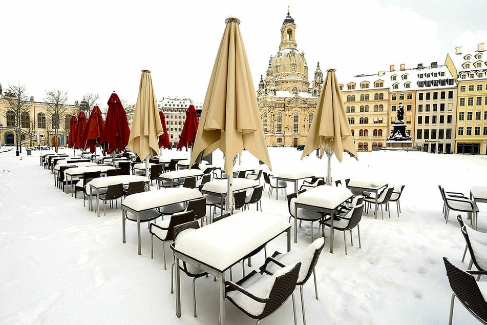 Schlummern auch weiterhin im Lockdown-Winterschlaf unter einer Schneedecke: verwaiste Tische und Stühle auf dem Dresdner Neumarkt an der Frauenkirche.