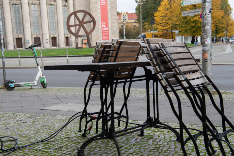 Zusammengeklappte Stühle stehen vor einem Restaurant am Rosa-Luxemburg-Platz in Berlin. Lieferservice ist ab Montag noch erlaubt, Speisen im Restaurant erst einmal untersagt.