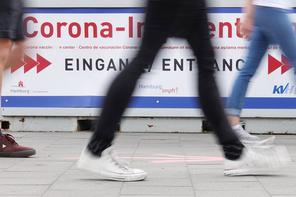 Passanten gehen zum Eingang des Corona Impfzentrums in Hamburg.