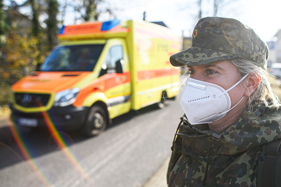 Eine Soldatin des Sanitätsdienstes der Bundeswehr vom Sanitätsregiment 1 Weißenfels aus Sachsen-Anhalt steht vor dem Städtischen Klinikum Görlitz während ein Rettungswagen vorbeifährt.