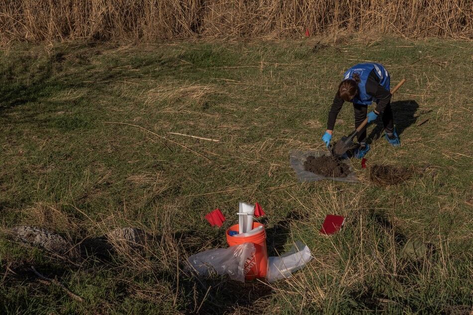 An ecological investigator collects soil in the area that was flooded following the Kakhovka dam explosion, for a war crime investigation into allegations of Russian ecocide, in Chornobaivka village, on November 7, 2023.