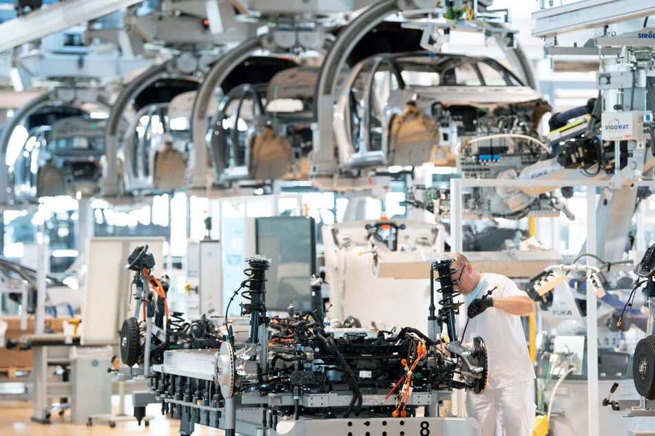 Ein Mitarbeiter arbeitet an der Karosserie eines E-Autos.