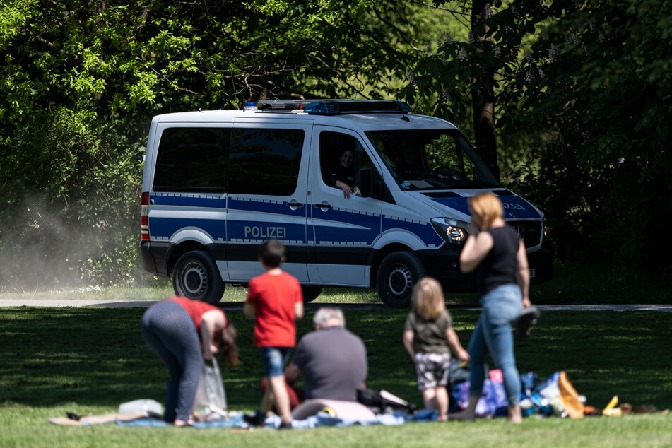 Die Polizei beobachtet kontrolliert in einem Park die Einhaltung der Corona-Schutzmaßnahmen.