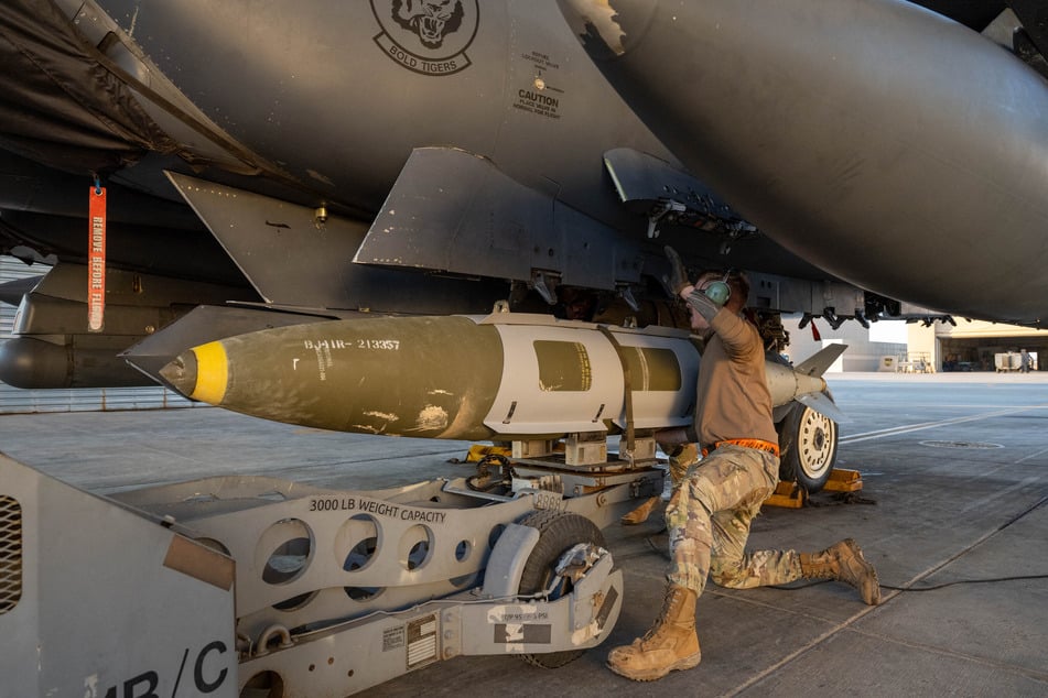 In this US Army photo released on December 19, 2025 and taken from an undisclosed location on December 18, 2025, a US Airman attaches a GBU-31 munitions system to an F-15E Strike Eagle in the US Central Command area of responsibility, in support of Operation Hawkeye Strike.