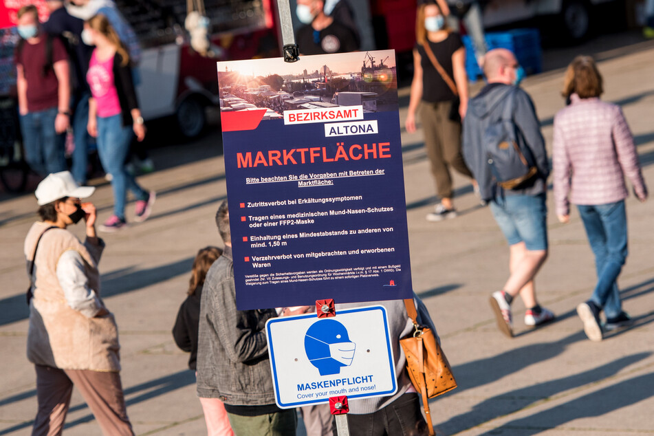 Auf dem beliebten Hamburger Fischmarkt hängt ein Schild mit Corona-Regeln.