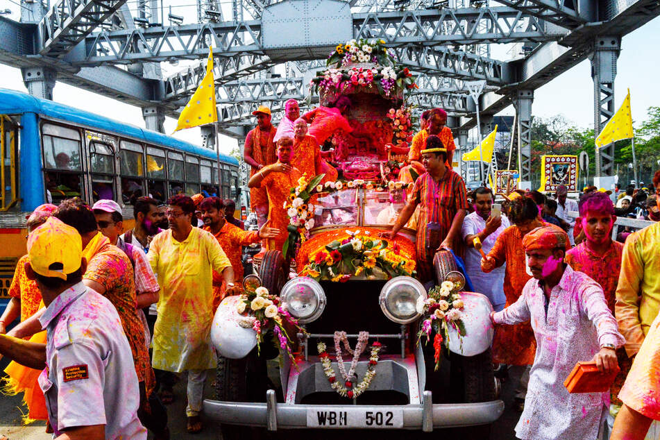 Figuren der Gottheiten Radha und Krishna werden bem Holi-Fest in Kalkutta (Indien) mit einem Auto gefahren.
