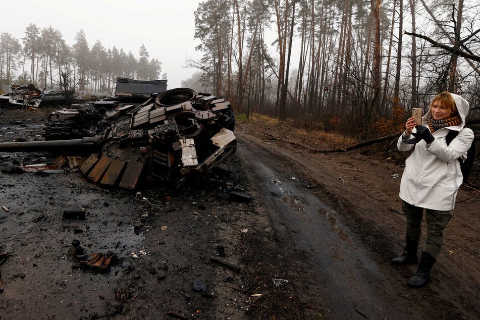 A woman films destroyed Russian tanks amid Russia's invasion of Ukraine in Dmytrivka village, west of Kyiv, Ukraine. REUTERS/Zohra Bensemra