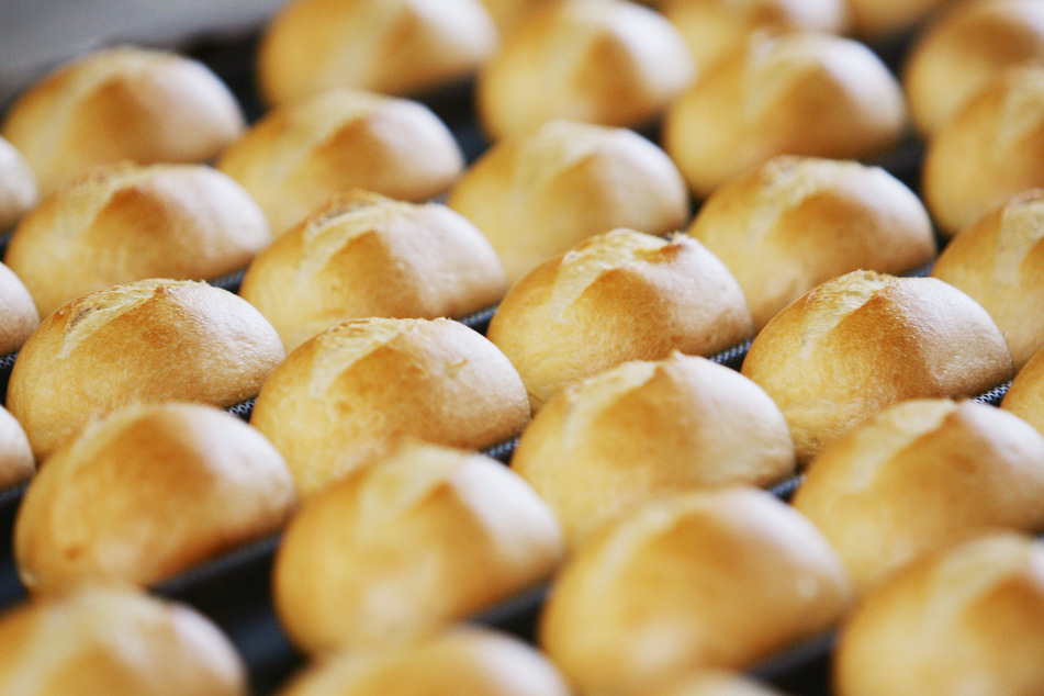 Brötchen auf dem Fließband in einer Großbäckerei in Ratingen kommen aus dem Ofen.