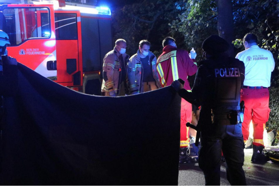Polizisten verhüllen mit einer Decke den Unfallort, während sich die Rettungskräfte um den am Boden liegenden Motorradfahrer kümmern.