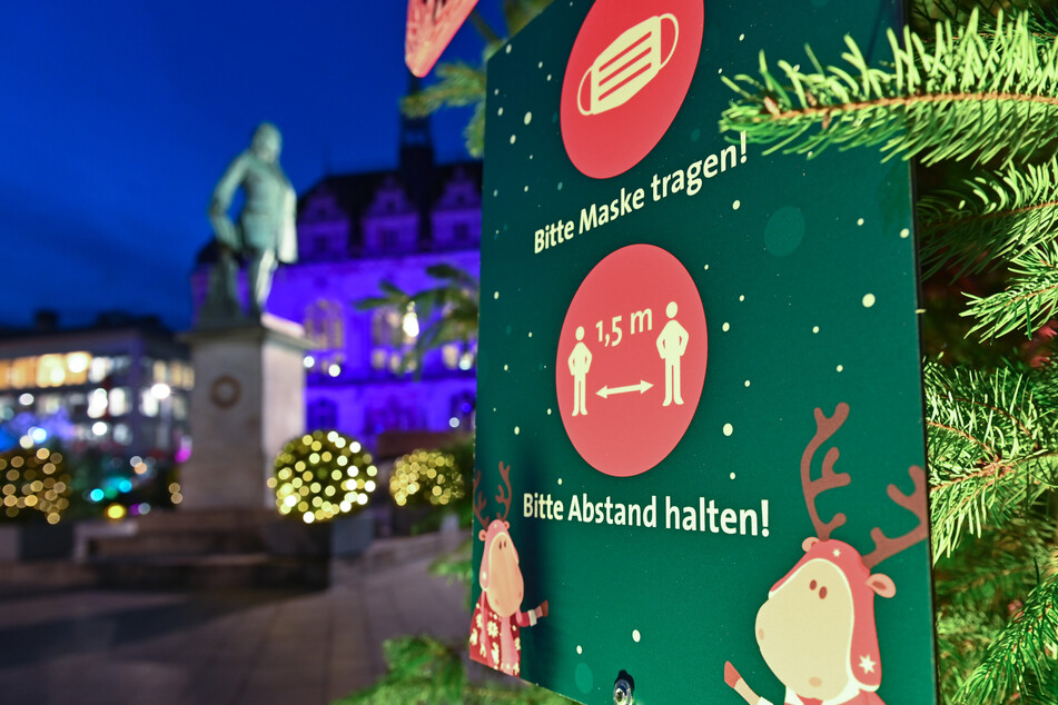 Ein Schild am Markt in Halle/Saale weist auf das Tragen eines Mund-Nasenschutzes und die Einhaltung des Sicherheitsabstandes hin.
