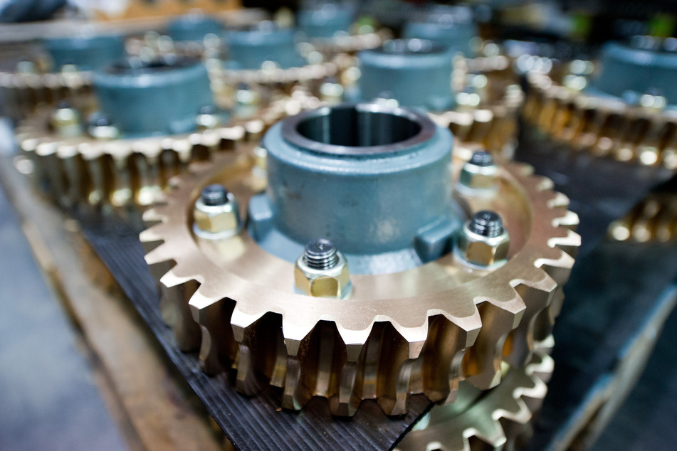 Schneckenräder, Teile eines Getriebes, liegen in der Produktionshalle eines Werkes.