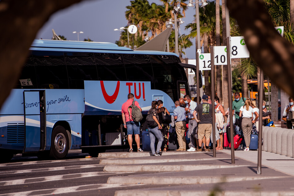 Touristen mit Mundschutz holen ihr Gepäck aus einem Bus des Tourismuskonzerns Tui nahe dem Flughafen Teneriffa.