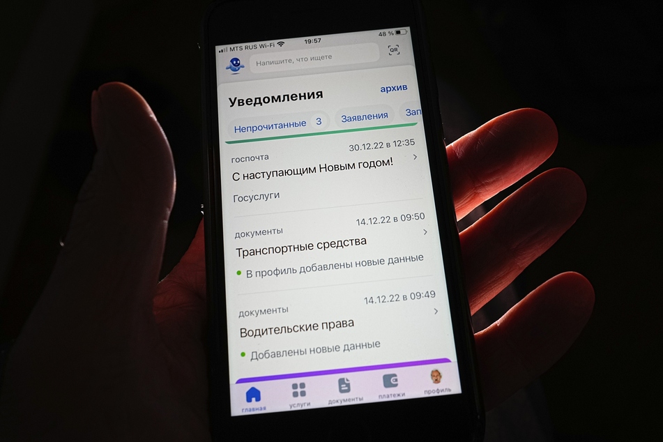 Eine Person hält ein Handy mit einem Bildschirm, der eine offene Seite der "Gosuslugi"-Website zeigt.