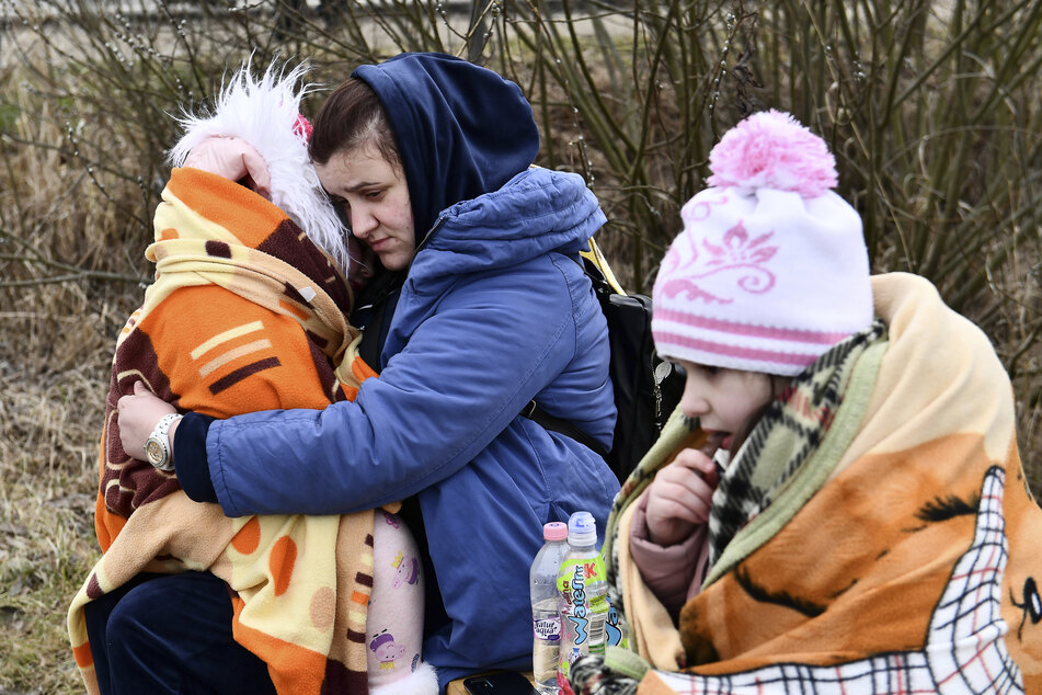 Ungarn, Beregsurany: Eine Mutter umarmt ihre Tochter an einem von örtlichen Freiwilligen betriebenen Kontrollpunkt, nachdem sie vor dem Konflikt in der Ukraine geflohen sind.