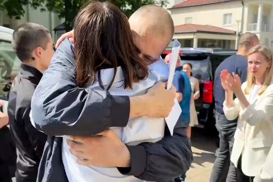 This handout photograph – which was made from a video published in the official Telegram channel of Belarusian opposition leader Svetlana Tikhanovskaya on Saturday – shows exiled Belarusian opposition leader Svetlana Tikhanovskaya hugging her husband Sergei Tikhanovsky in an unnamed place in Lithuania.