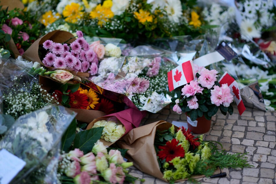 Mit Flaggen geschmückte Blumen bei der Gedenkfeier für die Opfer der entgleisten Standseilbahn.