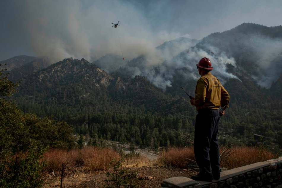Feuerwehrhauptmann James Klosek von der Feuerwehr des Bezirks Santa Barbara County steht auf einer Mauer und beobachtet einen Hubschraubereinsatz zum Löschen eines Waldbrandes des sogenannten El Dorado Feuers.