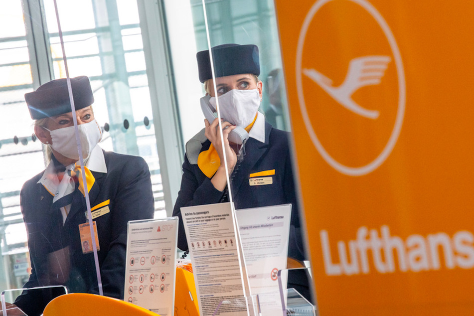 Zwei Lufthansa-Mitarbeiterinnen mit Mund-Nasen-Sschutzmaske und hinter Plexiglasscheiben in München.