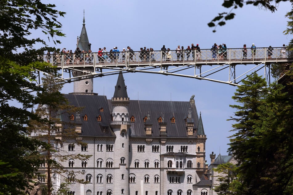 Touristen stehen auf der Marienbrücke vor dem Schloss Neuschwanstein.