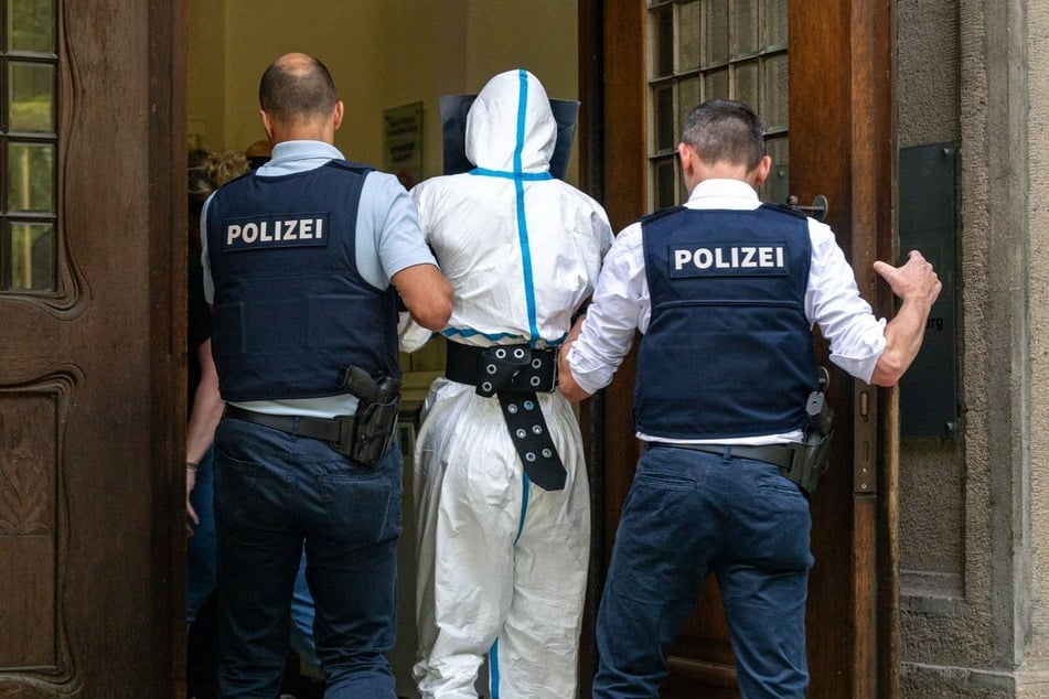 Der Täter wurde mit einem weißen Schutzanzug bekleidet abgeführt.