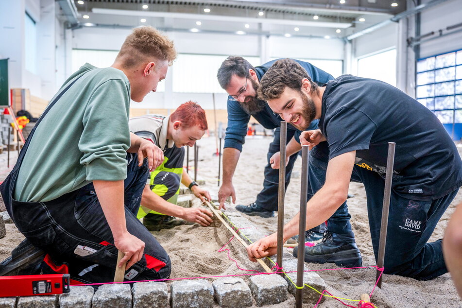 Die Straßenbau-Azubis Jonas Schneider (18, v.l.), Erik Seidel (19) und Jeremias Riedel (20) arbeiten mit Ausbilder Philipp Schade (39) in der neuen Straßen- und Tiefbauhalle der HWK Chemnitz.