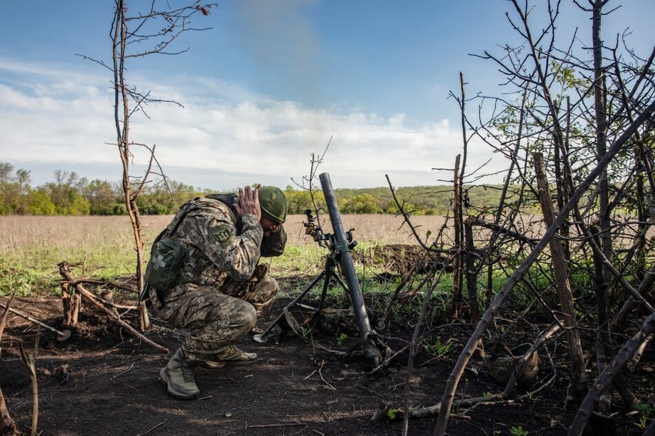 Ein Soldat einer Mörser-Einheit der ukrainischen Streitkräfte hält sich die Ohren zu, während er auf feindliche Stellungen in den Vororten der Stadt Bachmut feuert.