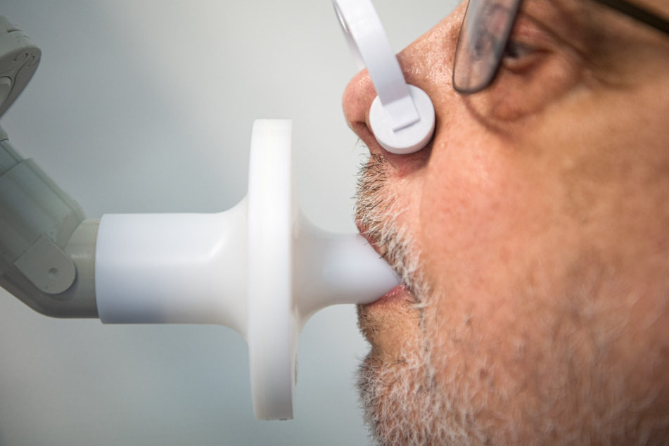 Ein Long-Covid-Patient sitzt zur Überprüfung seiner Lungenfunktion in einem Bodyplethysmographen.