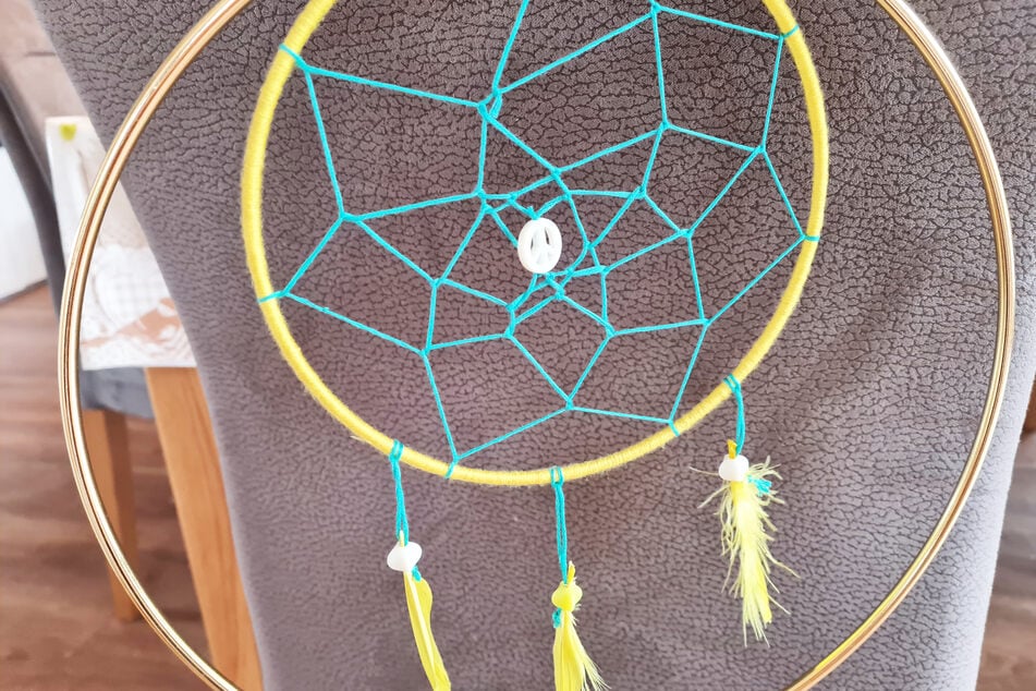 Dieser Traumfänger für Kinder besteht aus zwei Ringen, einem Netz, Perlen, Federn und gesammelten Zweigen.