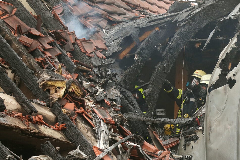 Feuerwehrleute suchen in einem beschädigten Wohnhaus nach Spuren.