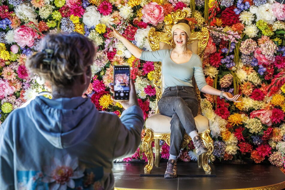 Zur Ausstellungseröffnung "Blütenwunder" in Freital lässt sich Hannah Löwe (19) feierlich an der Blumenwand knipsen.