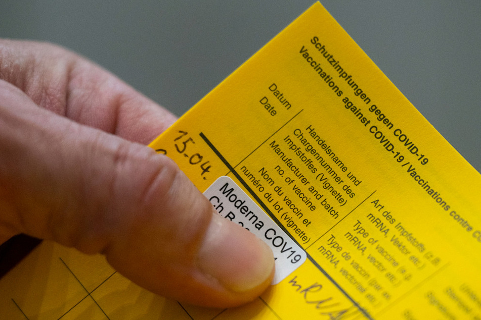Ein Aufkleber der auf eine Impfung mit dem Impfstoff Moderna hinweist, klebt in einem Impfpass.