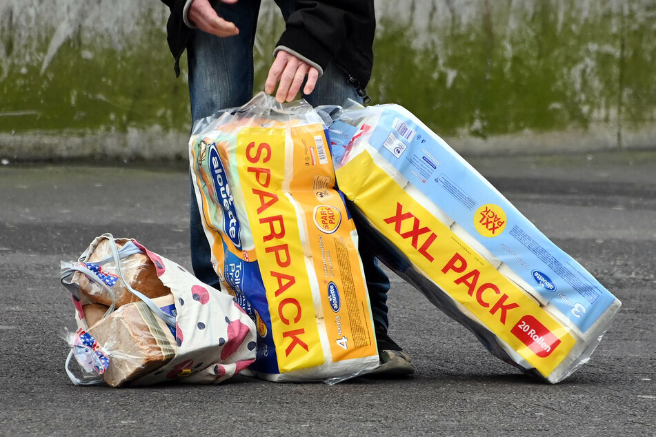 Eine Person steht in der Innenstadt mit zwei XXL-Packungen mit Toilettenpapier an einer Straßenbahnhaltestelle. Zu Beginn der Corona-Krise waren die Klopapier-Regale von Supermärkten wochenlang leer.