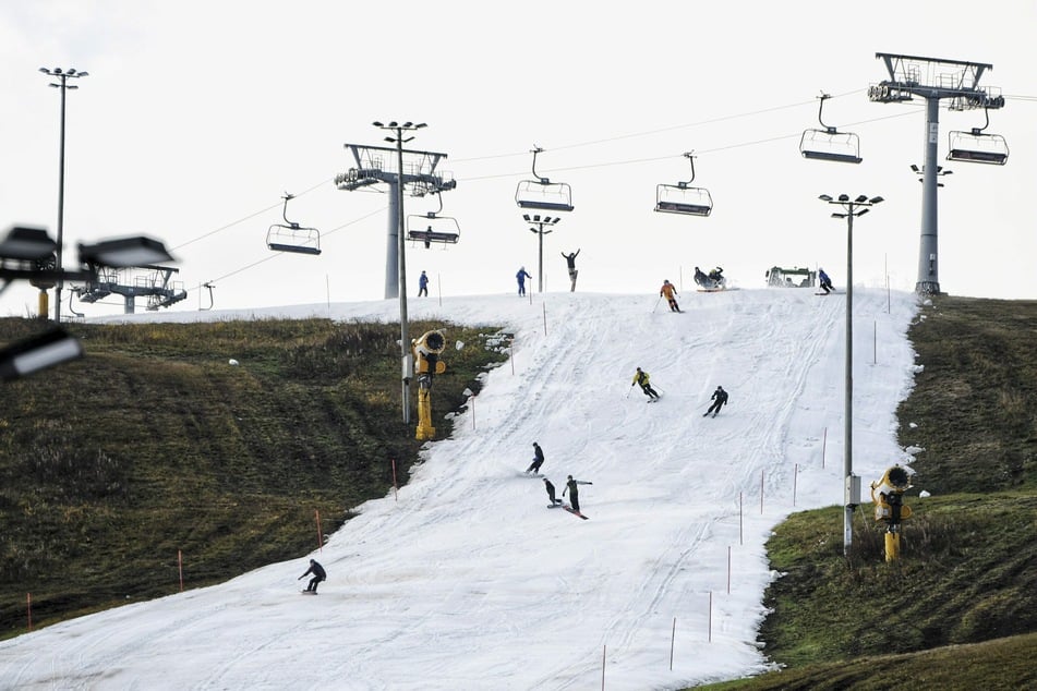 Snowboarder und Skifahrer fahren auf einer Piste.