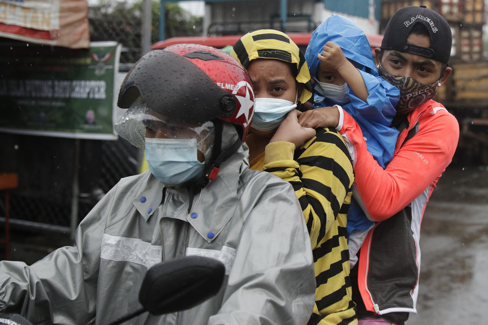 Residents of a coastal community in Manila escape on a motorcycle.