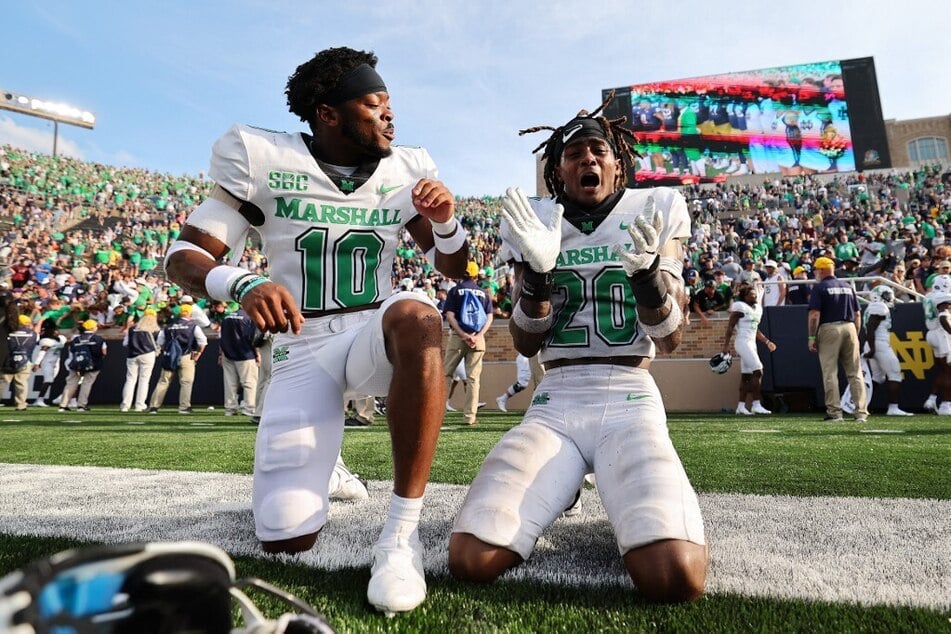 Joshua Bowers and Andre Sam of the Marshall Thundering Herd celebrate after defeating the Fighting Irish 26-21 at Notre Dame Stadium.