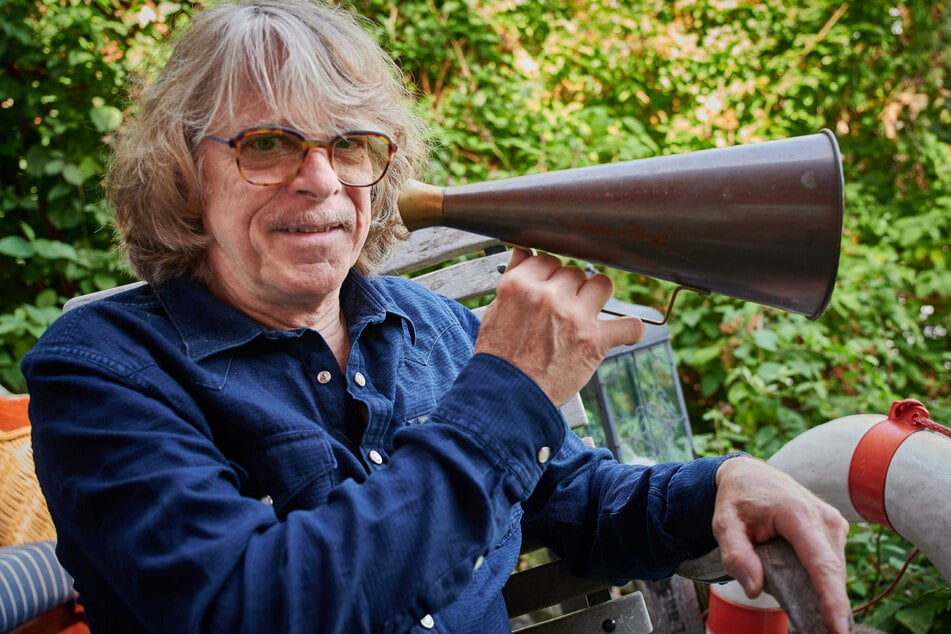 Musician and comedian Helge Schneider sits on the terrace of his apartment with a megaphone in hand.  Schneider has asked Finance Minister Scholz (62, SPD) to calculate Corona's artist aid differently than advertised.