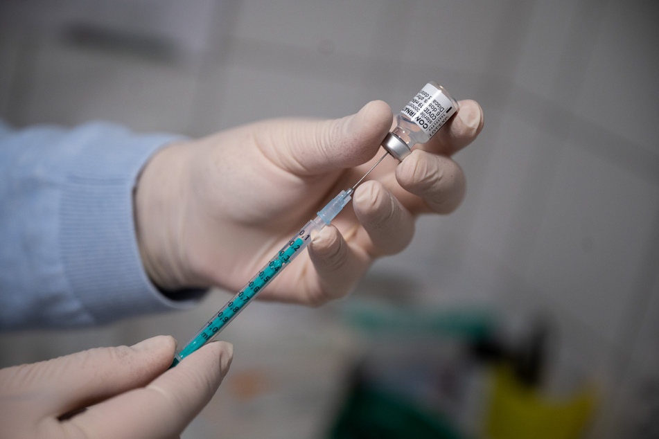 Ein Arzt zieht in einer Hausarztpraxis eine Spritze mit dem Impfstoff von Pfizer/Biontech auf.
