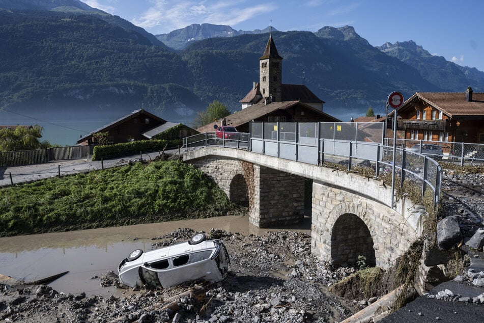 Unwetter in der Schweiz: Ein Auto liegt im verschütteten Schienenbereich der Zentralbahn Interlaken-Meiringen, oberhalb der Kirche von Brienz.