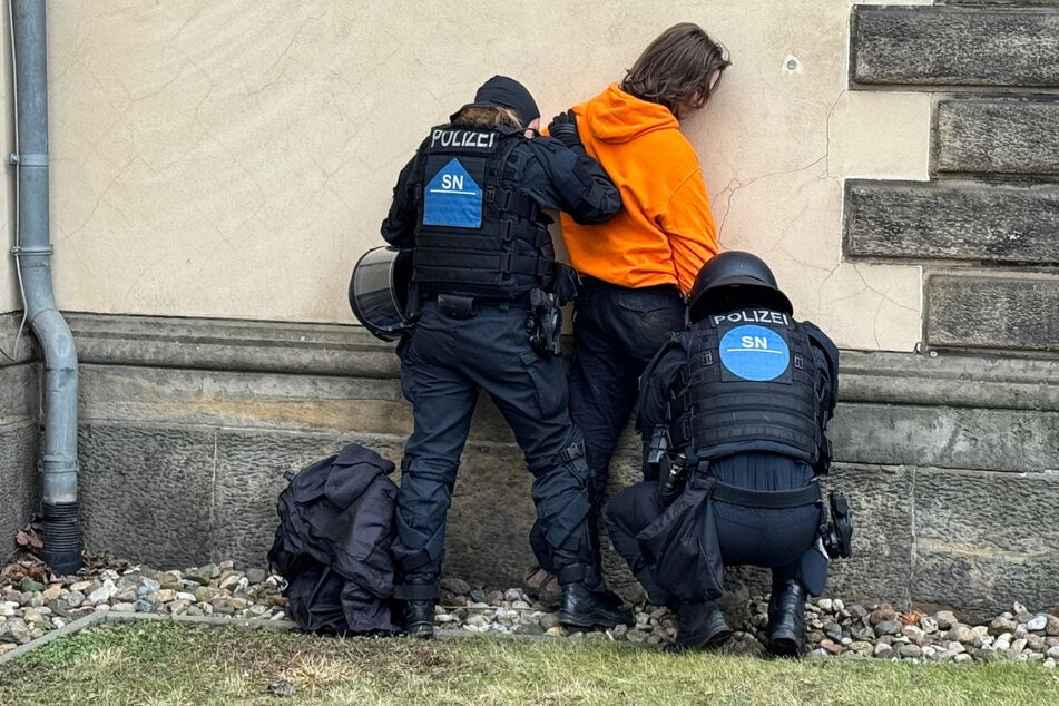 Dieser Demonstrant wird von der Polizei durchsucht.
