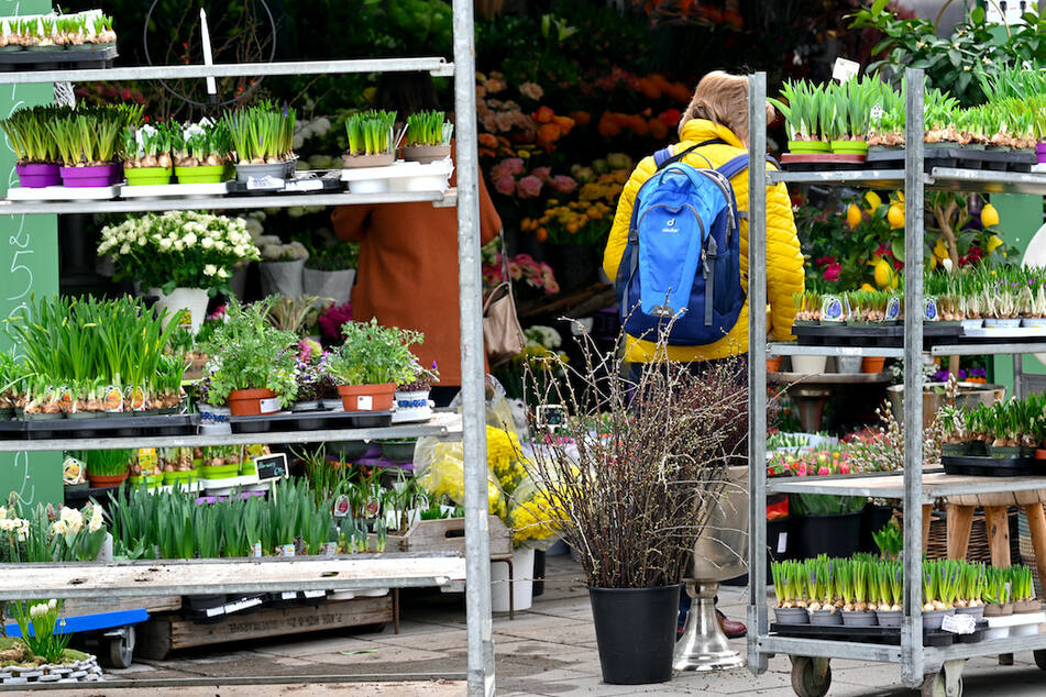 Eine Frau steht auf dem Viktualienmarkt vor einem Blumenladen.