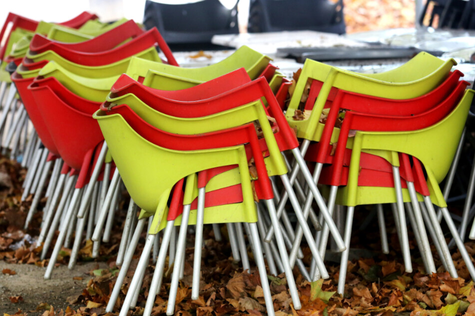 Herbstlaub bedeckt Stühle vor einem Restaurant im nordrhein-westfälischen Essen.